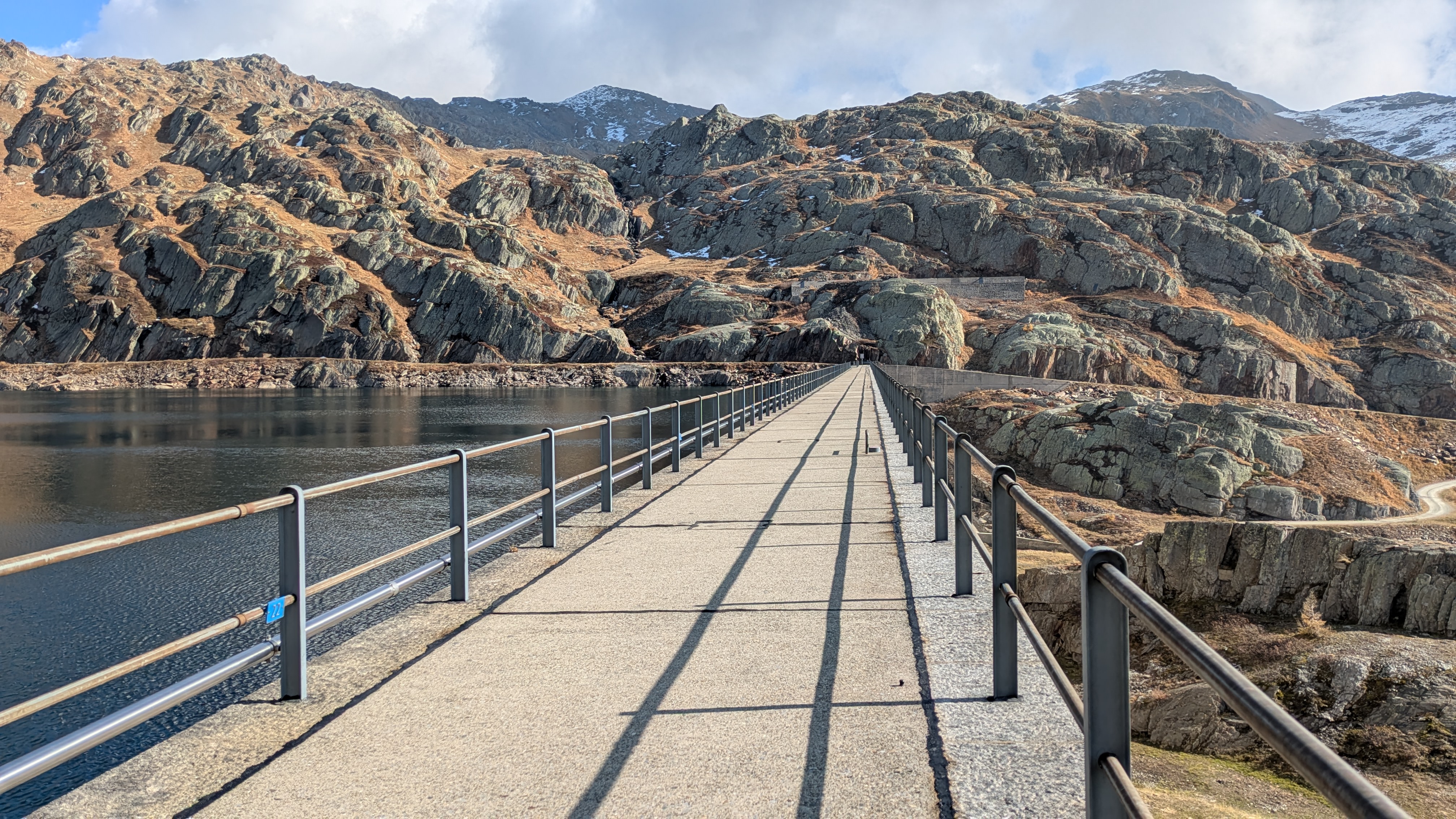 Lago della Sella kurz oberhalb des Gotthardpasses mit der Brücke, die auf die andere Seite des Seeufers führt.