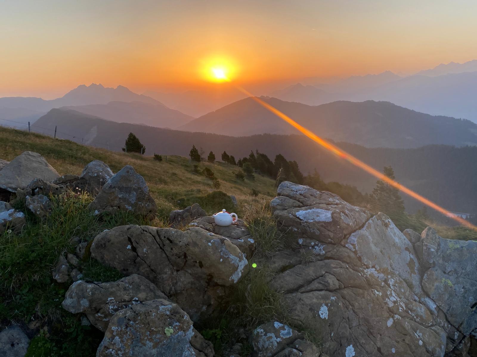 Strahlende Morgensonne mit weißem Zentrum und goldenem Strahlenkranz im orange-roten Himmel beim Sonnenaufgang am Rickhubel